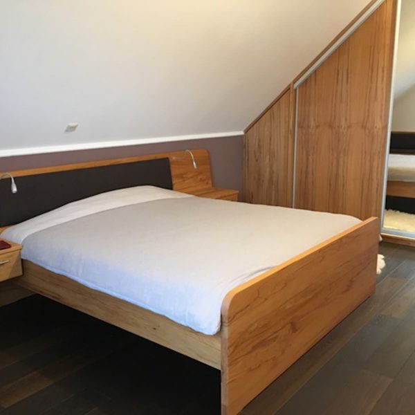 Massivholz-Schlafzimmer in Kernbuche mit Schiebetorschrank in der Schräge sowie Bett und Bank, geölt